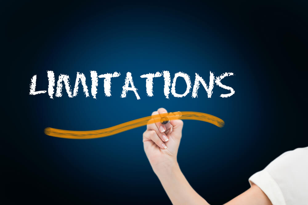 Businesswoman writing the word limitations against blue background with vignette