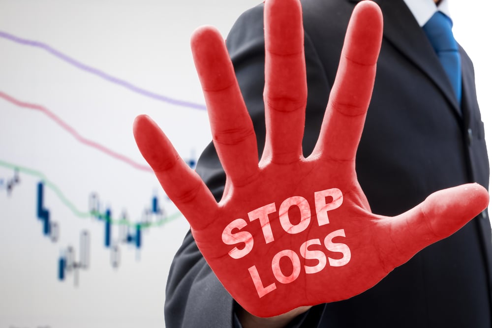 Businessman in gray suit raise his hand saying ' stop loss ' on his red palm